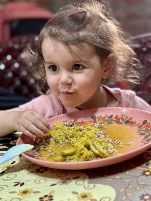 Child enjoying dal and rice at the table