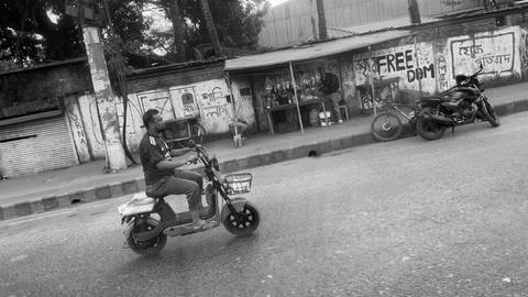 Street scene in black-and-white—rider on scooter passing stalls